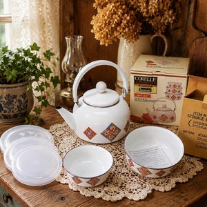 May include: A white enamel tea kettle and two matching bowls with a geometric orange and blue pattern. The set includes three translucent plastic lids and a cardboard box labeled Corelle Coordinates Sand Art, Item # S.006 Storage Bowl Set.