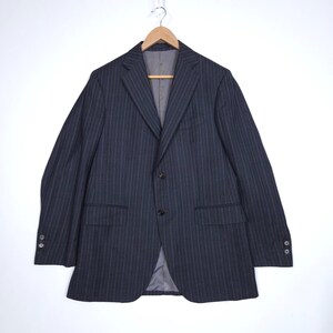 May include: A navy blue pinstripe blazer hanging on a wooden hanger. The jacket features two front pockets, two buttons, and buttons on the sleeves. The interior lining is a light grey colour. The blazer is a classic style.