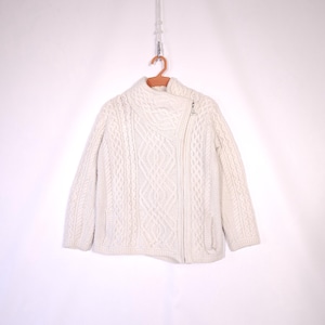 May include: A white cable knit cardigan with a zip closure. The cardigan has a high collar and a slightly asymmetrical hem.