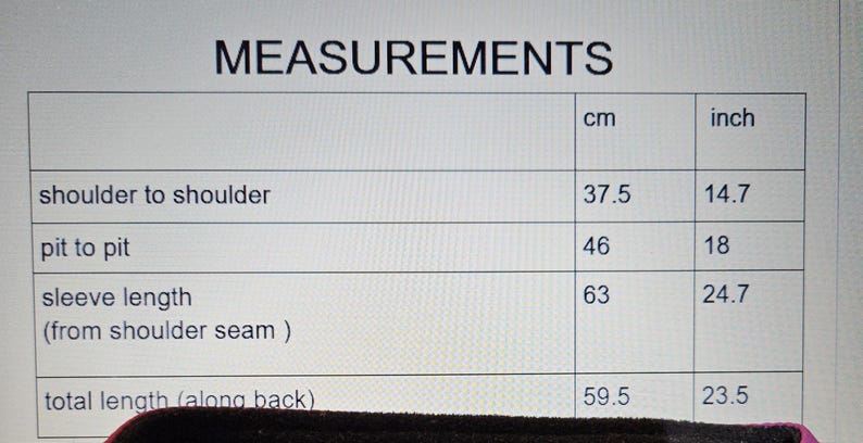 May include: A table of garment measurements in centimeters and inches. Measurements include shoulder to shoulder (14.7 in/37.5 cm), pit to pit (18 in/46 cm), sleeve length (24.7 in/63 cm), and total length (23.5 in/59.5 cm).