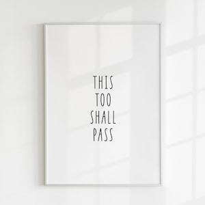 May include: A framed print with the text "THIS TOO SHALL PASS" in black lettering on a white background.