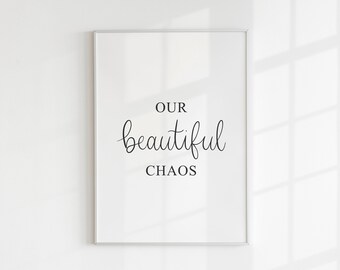 Op de afbeelding: Een witte ingelijste print met de tekst "OUR beautiful CHAOS" in zwarte kalligrafie.