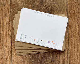 May include: A stack of blank note cards with a brown kraft paper backing. The note cards have a floral border with a bee and the text "Vintage Text Message" at the top.