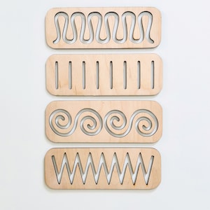 May include: Four wooden tracing boards with different patterns cut out. The patterns include wavy lines, straight lines, spirals, and zigzags.