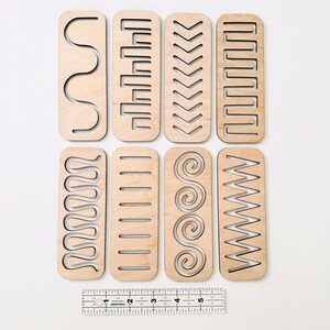 May include: Eight wooden strips with different patterns cut out. The strips are approximately 5 inches long and 1 inch wide. The patterns include wavy lines, rectangles, chevrons, and spirals.