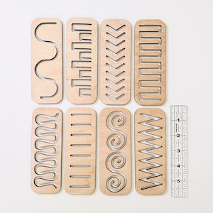 May include: Eight wooden rectangular blocks with different patterns cut out. The patterns include wavy lines, zigzags, spirals, and straight lines. A ruler is included for scale.