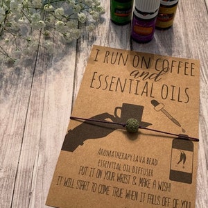 May include: A brown card with the text "I run on coffee and essential oils" and a drawing of a hand holding a lava bead bracelet. The card also includes the text "Aromatherapy lava bead essential oil diffuser. Put it on your wrist & make a wish! It will start to come true when it falls off of you! Alyssa Ashley Designs."