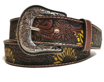 May include: A brown leather belt with a silver buckle. The belt features a sunflower design with yellow and brown accents. The buckle has an ornate floral pattern. The belt is approximately 1.5 inches wide.
