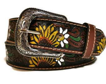 May include: A brown leather belt with a silver buckle and a floral design featuring sunflowers and daisies. The belt is decorated with hand-painted details in yellow, green, white, and brown.