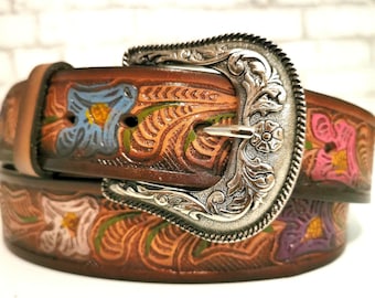 May include: A brown leather belt with a silver buckle and floral tooled design. The belt is decorated with colorful flowers in shades of blue, pink, and purple.