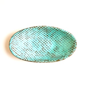 May include: A light blue oval ceramic dish with a textured, snakeskin-like pattern.