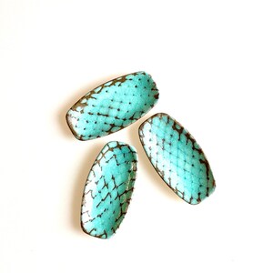 May include: Three small, oval-shaped ceramic dishes with a turquoise glaze and brown crackle finish.