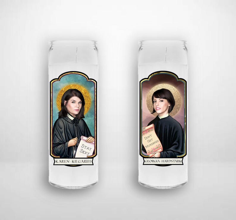 May include: Two glass candle holders with images of women. The candle holder on the left features a woman with dark hair and the text "Stay Sexy" and "Karen Kilgariff". The candle holder on the right features a woman with dark hair and the text "Don't Get Murdered" and "Georgia Hardstark".