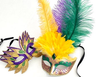 Peut inclure: Deux masques de carnaval avec des accents de paillettes dorées et violettes. Les masques sont décorés de plumes dans les tons de vert, violet et jaune.