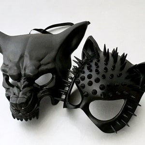 Puede incluir: Dos m&aacute;scaras negras. Una es una m&aacute;scara facial completa con un dise&ntilde;o feroz y animalista. La otra es una media m&aacute;scara con p&uacute;as afiladas. Ambas m&aacute;scaras tienen un acabado mate y probablemente sean para uso de vestuario o teatral.