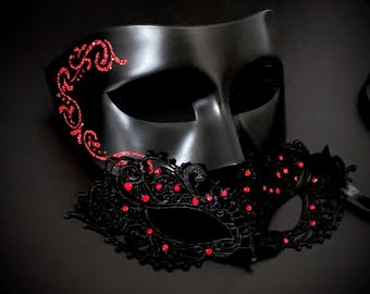 May include: Two black masquerade masks. One is a solid black mask with red glitter accents. The other is a black lace mask with red rhinestones. Both masks are on a black surface.