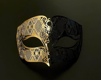 May include: A decorative Venetian mask, split vertically into gold and black halves. The gold side features intricate openwork diamond and floral patterns. The black side mirrors the diamond design. The mask is designed for eye coverage and is set against a dark background.