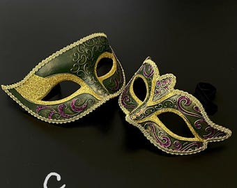 Peut inclure: Deux masques de mascarade avec des accents dorés et violets sur un fond noir. Les masques sont verts avec des paillettes dorées et des motifs complexes.