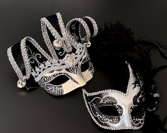 May include: Two masquerade masks, one black and silver with a jester's hat design and the other black and silver with feathers.