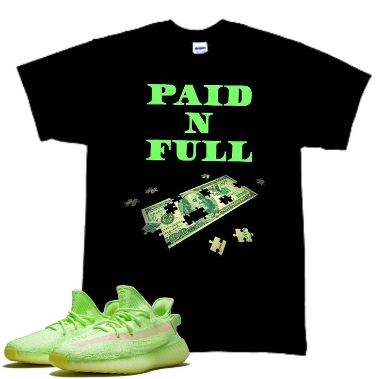 May include: Black t-shirt with the text "PAID N FULL" in green, a green dollar bill puzzle, and a pair of green and white sneakers.