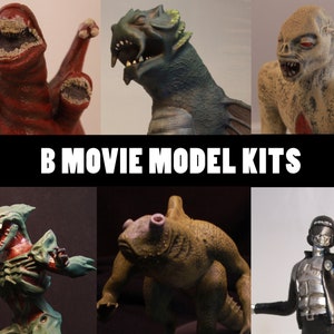 May include: A collection of six monster model kits. The models are in various colours and designs, including a red creature with a gaping mouth, a green and blue sea monster, and a zombie. The text "B MOVIE MODEL KITS" is displayed.