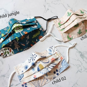 May include: Three different patterned fabric face masks with elastic ear loops. The masks are labeled "child jungle", "child 01", and "child 02".