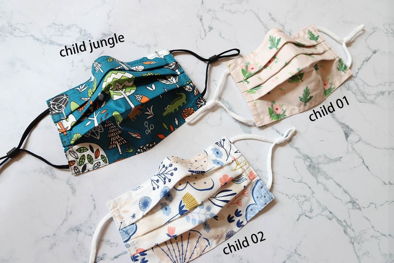 May include: Three different patterned fabric face masks with elastic ear loops. The masks are labeled "child jungle", "child 01", and "child 02".