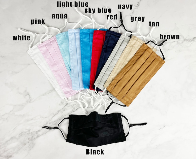 May include: A set of 10 face masks in various colors, including white, pink, aqua, light blue, sky blue, red, navy, grey, tan, and brown. A black face mask is also shown in the center of the image.  The masks are all pleated and have elastic ear loops.