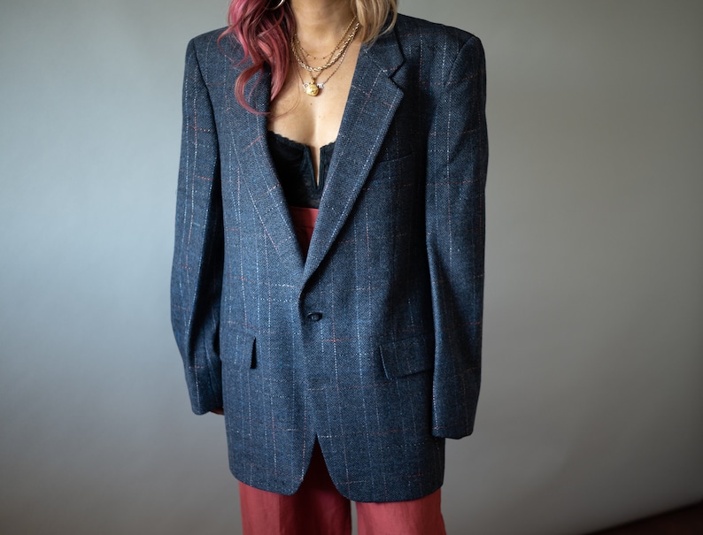 Op de afbeelding: Een blauwe blazer met een subtiel ruitpatroon. De blazer heeft een enkele knoopsluiting en een revers.