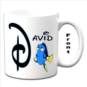 Peut inclure: Une tasse en céramique blanche avec un logo Disney noir et un personnage bleu Dory du film Le Monde de Nemo. La tasse est personnalisée avec le nom "DAVID" imprimé dessus.