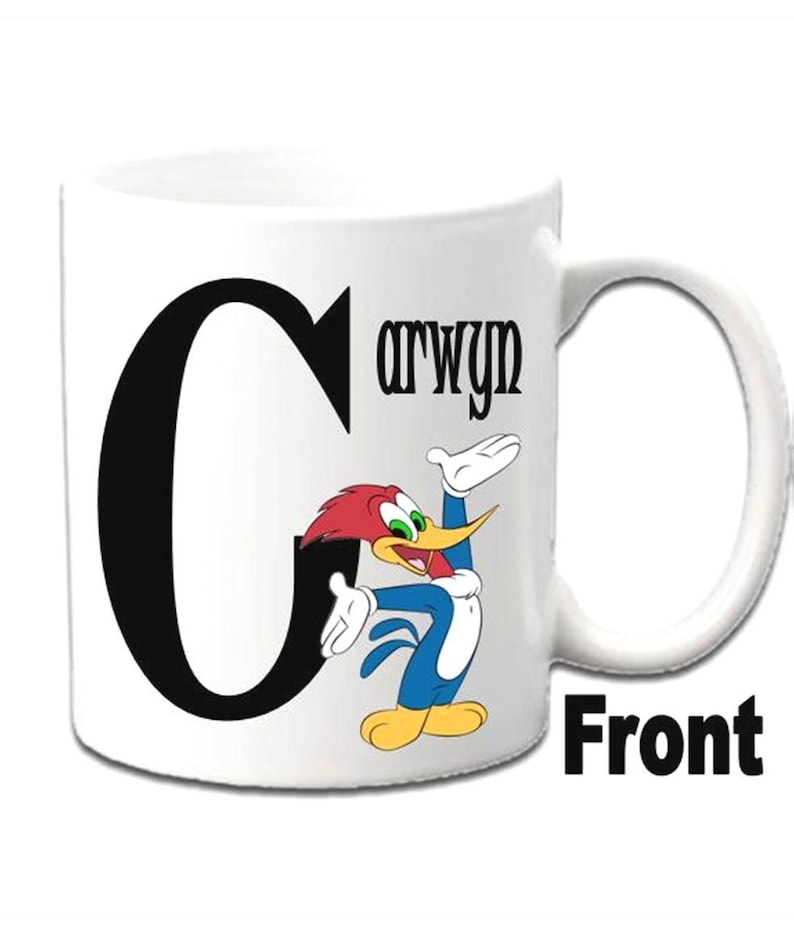 K&ouml;nnte beinhalten: Eine wei&szlig;e Keramiktasse mit einem schwarzen Buchstaben C und einem Cartoon-Bild von Woody Woodpecker. Die Tasse tr&auml;gt den Namen "Carwyn".