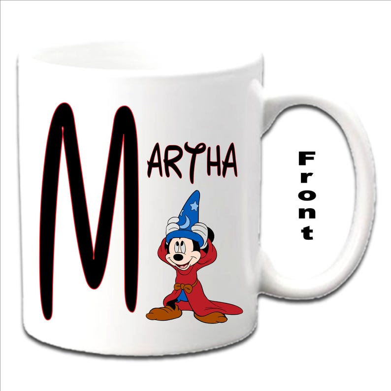 May include: White ceramic mug with a black letter "M" and the name "MARTHA" printed in black. A cartoon image of Mickey Mouse dressed as a sorcerer is on the mug. The word "Front" is printed on the handle of the mug.