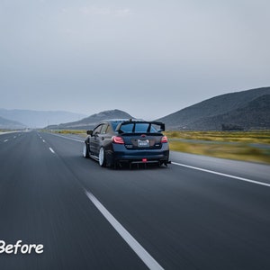 May include: A dark blue Subaru WRX STI driving on a highway with mountains in the background. The car has a rear spoiler and a license plate that reads "WRX STI".