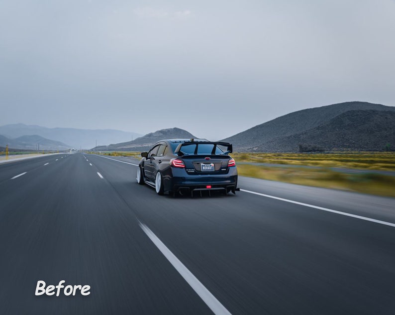 May include: A dark blue Subaru WRX STI driving on a highway with mountains in the background. The car has a rear spoiler and a license plate that reads "WRX STI".