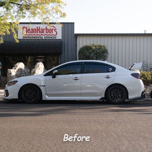 May include: A white Subaru WRX with black wheels and tinted windows parked in front of a building with the sign "CleanHarbors Environmental Services".