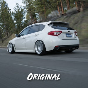 K&ouml;nnte beinhalten: Ein wei&szlig;er Subaru Impreza WRX STI Kombi f&auml;hrt auf einer kurvigen Stra&szlig;e durch einen Wald. Das Auto hat einen schwarzen Heckspoiler und schwarze Felgen.