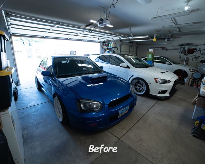 May include: A blue Subaru Impreza WRX STI and a white Mitsubishi Lancer Evolution parked in a garage. The Subaru has a white racing stripe on the hood and the Lancer has blacked-out windows.