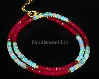 May include: A double-strand necklace with red and white beads. The necklace is made of red gemstone beads and white opal beads. The necklace has a gold clasp.