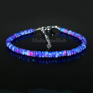 Peut inclure: Un bracelet délicat composé de perles d'opale bleue irisées. Le bracelet est doté d'un fermoir argenté et mesure environ 18 cm de long. MultistoneHub est imprimé sur le bracelet.