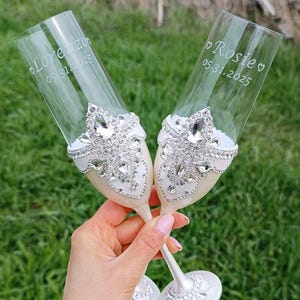 Bruiloft fluiten en taartsnijset gegraveerde witte champagneglazen eenheidskaarsenset verzilverd bord en vorken gepersonaliseerde taartserverset