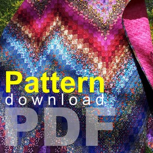 以下が含まれることがあります： 紫、ピンク、青、赤の色合いが特徴的な、シェブロン柄のカラフルなキルト。キルトは花柄で、「Pattern download PDF」の文字が画像に重ねられています。キルトは屋外に展示されています。