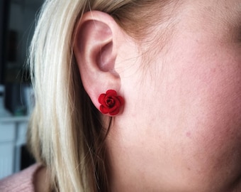 May include: A pair of red rose stud earrings. The earrings are small and delicate, and they would make a great gift for a special occasion.