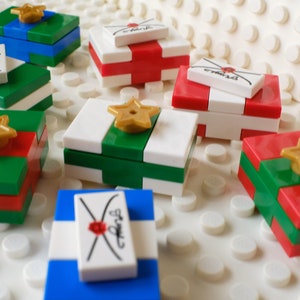 May include: A collection of small, colorful gift boxes with gold stars and envelopes. The boxes are made of Lego bricks and are decorated with red, green, and white stripes.
