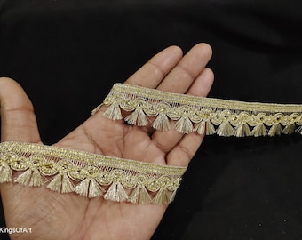 Op de afbeelding: Gouden trim met een franje van kwastjes. De trim is versierd met kleine, glanzende kralen.