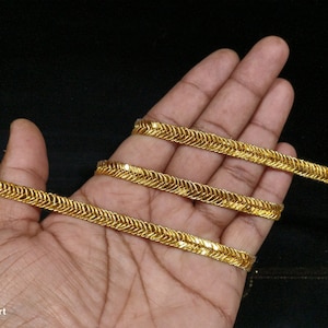 May include: Gold-coloured trim with a zig-zag pattern. The trim is shown wrapped around a hand.