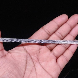 May include: A silver chain with a herringbone pattern.