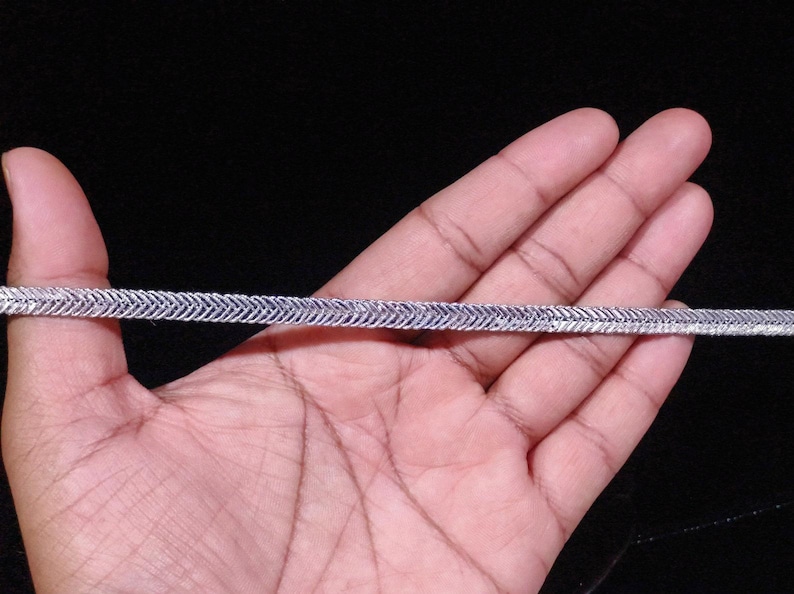 May include: A silver chain with a herringbone pattern.