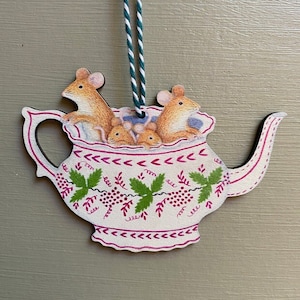 May include: A white ceramic teapot ornament with a pink trim and green vine design. Four brown mice are sitting inside the teapot.