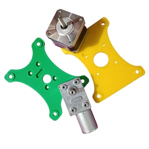 Puede incluir: Un conjunto de placas de montaje impresas en 3D, verde y amarillo, para un motor paso a paso y un motor de engranajes. El motor paso a paso es cuadrado y tiene un eje plateado. El motor de engranajes es redondo y tiene un eje plateado.