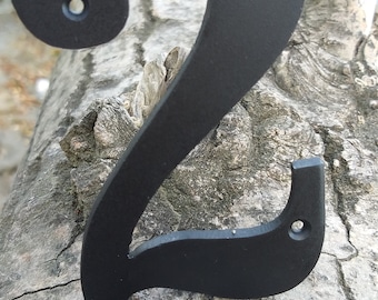 May include: Black metal house number two, with a decorative swirl design, mounted on a tree trunk.